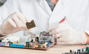 Close-up of technician holding computer chip and motherboard.