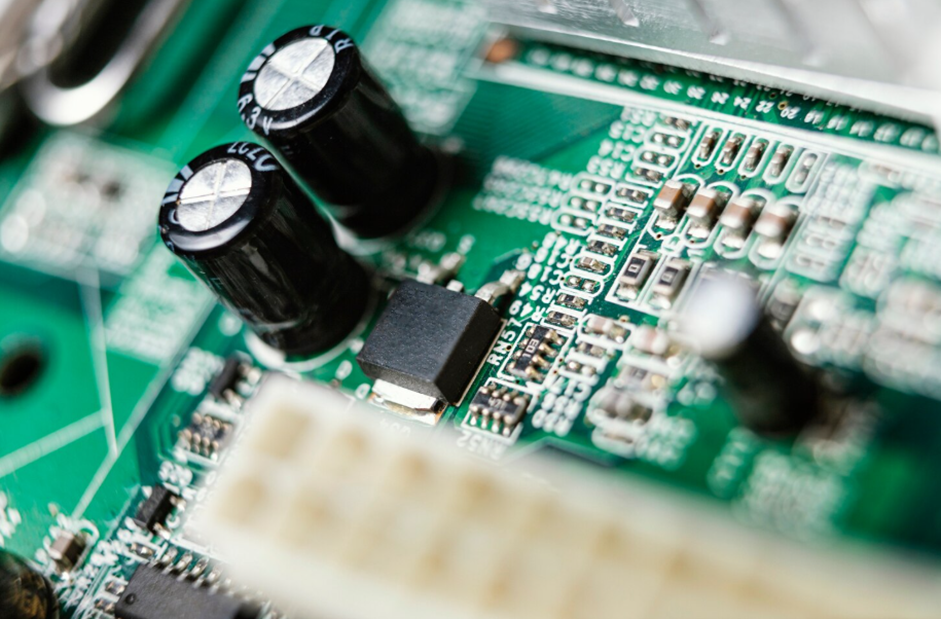 A close-up photograph of a green electronic circuit board. 