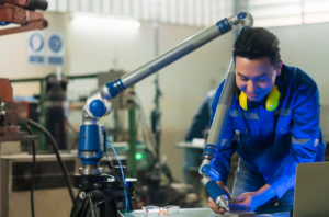 Technician operates robotic arm in manufacturing factory